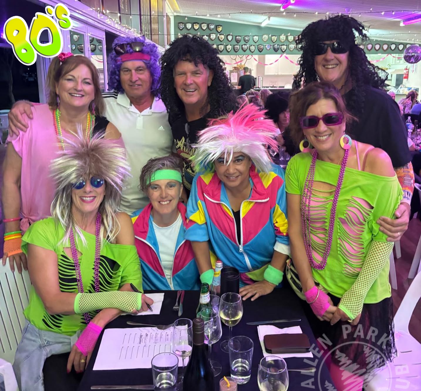 Members in bright wigs and 80's tracksuits